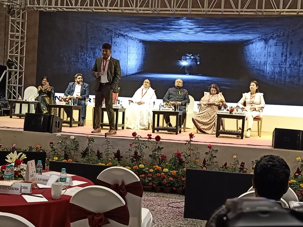 Naseer Khan speaking on stage at the World Confluence of Humanity, Power, and Spirituality, inspiring the audience with a motivational talk on personal growth.